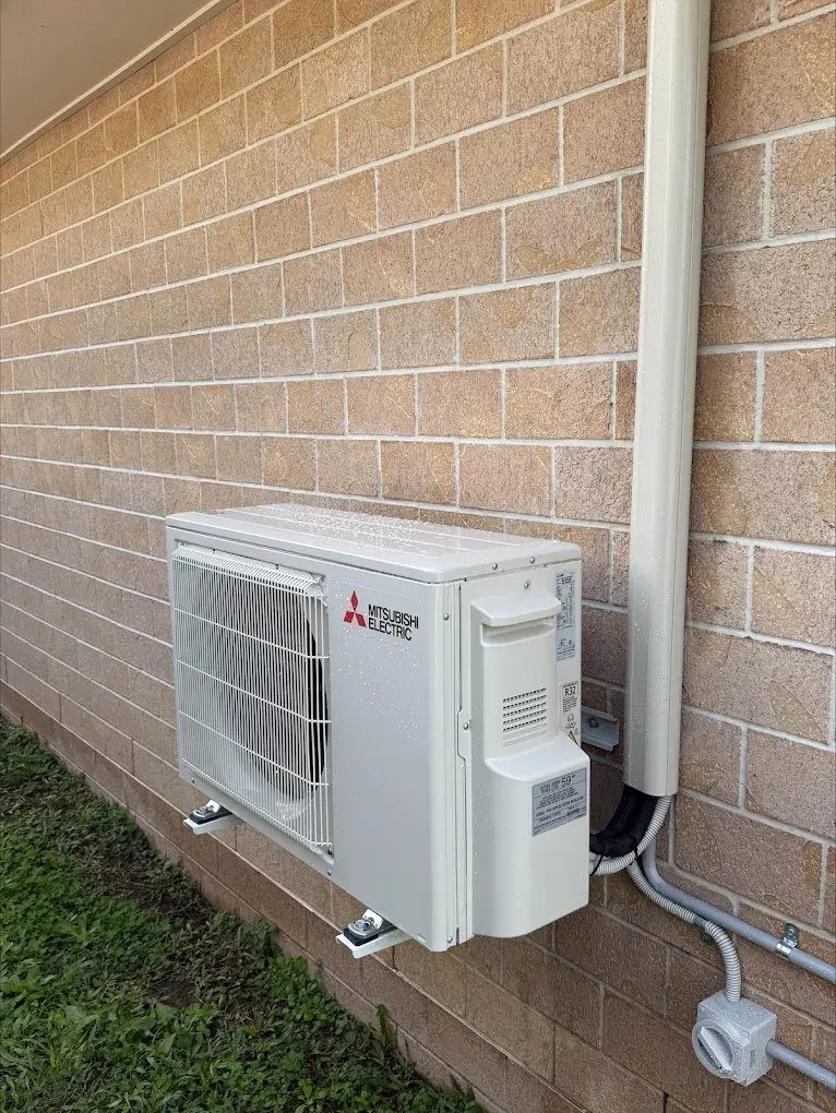 Outdoor split system condenser unit mounted on a Brisbane home exterior wall
