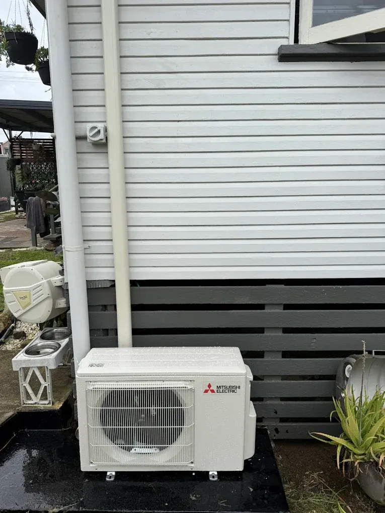 Air conditioning install with conduit and pipework run cleanly along external wall